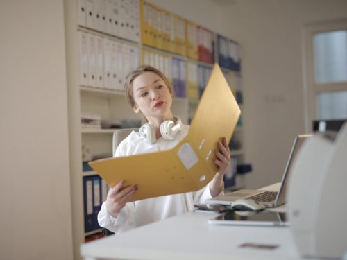 thoughtful female office worker with folder in workplace